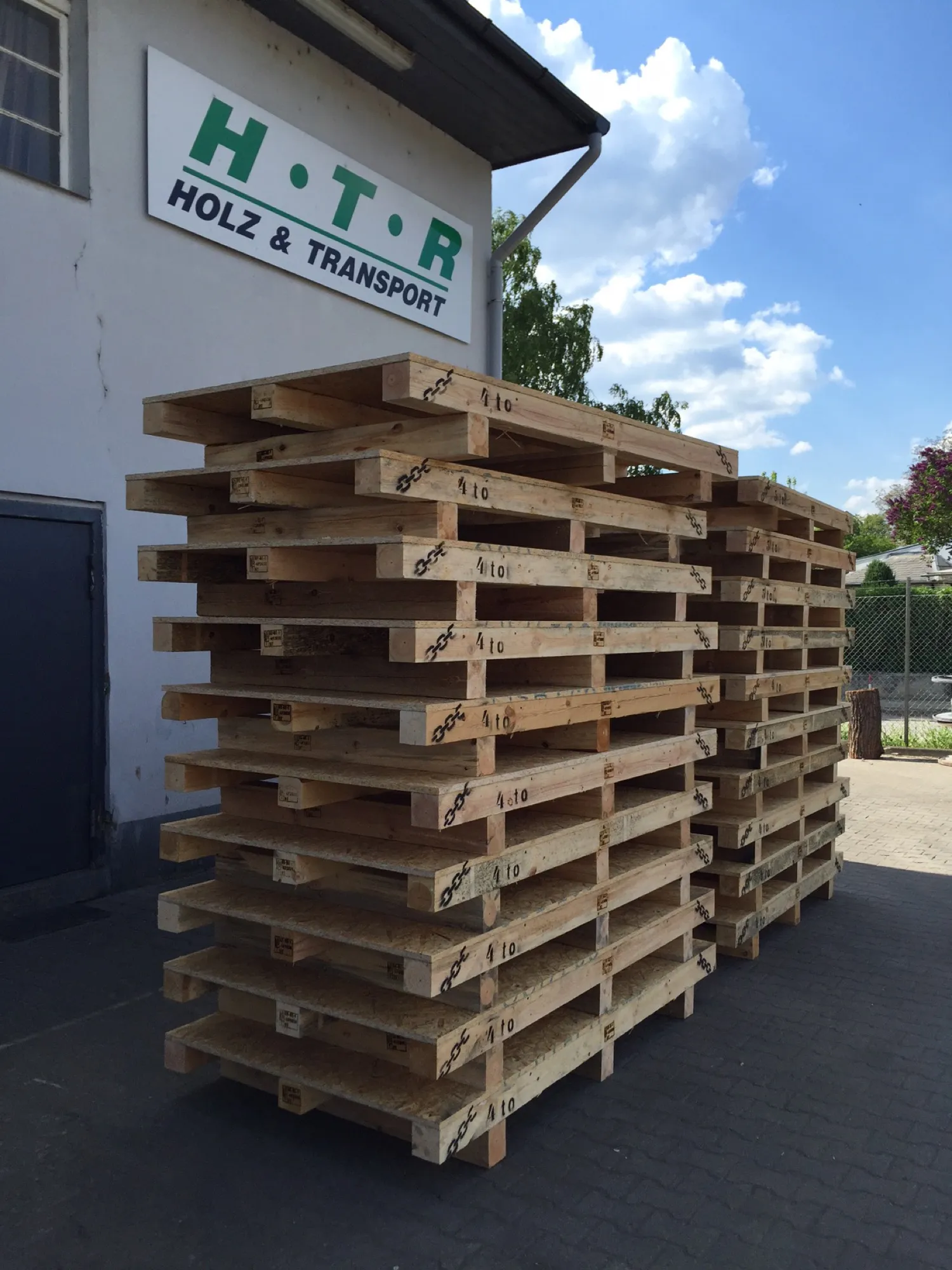 Firmengebäude der HTR Holz & Transport mit gestapelten Spezialpaletten